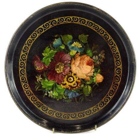 A 19thC painted papier mache plate, in the manner of Bettridge, of circular form, centred by a bouquet of flowers with an outer gilt scroll border, unmarked, 26cm diameter.