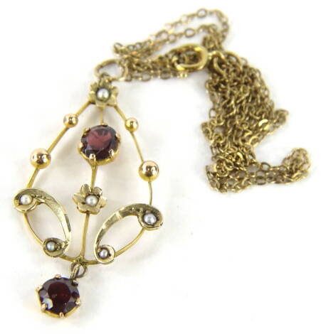 An early 20thC drop pendant of pear shaped form, claw set with a lower garnet and set with a further garnet and small pearls, 3cm high, on a slender necklace, marked 9ct.