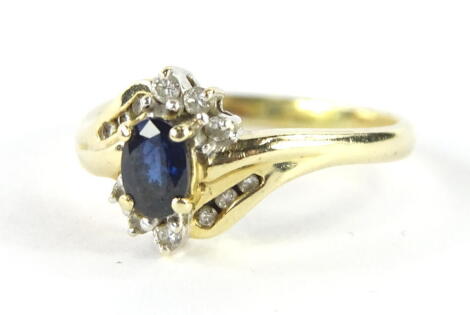 A ladies dress ring, claw set with a central blue stone, set with six small diamonds with six further diamonds to the crossover setting, size P, unmarked, 4g all in.