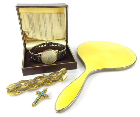 A George V silver and yellow enamel hand mirror, of shaped form, Birmingham 1929, 25cm wide, a Cymaflex gentleman's wristwatch with pierced bracelet, baton pointers and numerals and subsidiary second hand, a cross brooch set with turquoise and an Art Deco