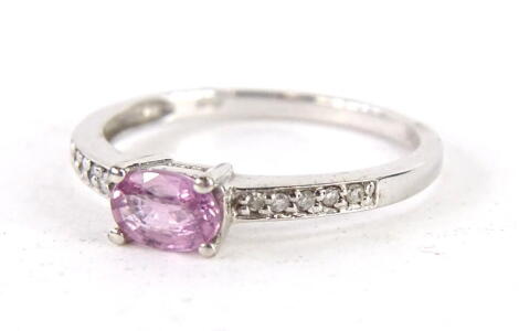 A 9ct white gold dress ring, claw set with a pink stone, flanked by white stones to each shoulder, size M, 2g all in.