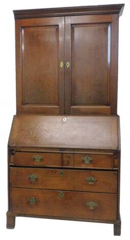 A George III oak bureau cabinet, the top with a moulded cornice above two panel doors, enclosing shelves and six small drawers, the base with a fall enclosing a fitted interior above two short and two long drawers on associated bracket feet, (AF), 102cm w