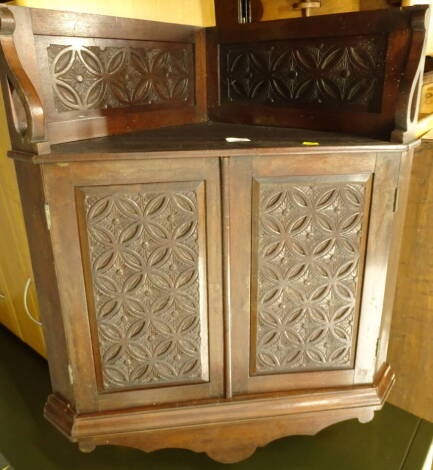 A 19thC walnut corner cabinet, carved with lozenges and roundels with two panelled doors and a shaped crest, 70cm wide.