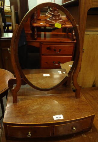 A late 19th/early 20thC mahogany dressing table mirror, the oval plate on shaped supports, the bow fronted base with two drawers on short bracket feet, 36cm wide.