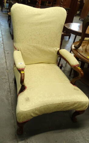 A walnut open armchair in the George III style, the cream damask padded back arm rest and seat with shepherd's crook arms on cabriole legs with pad feet.