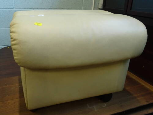 A cream leather ottoman or footstool, with hinged lid on plastic castors, stamped Ekorns, probably Stressless, 44cm wide.