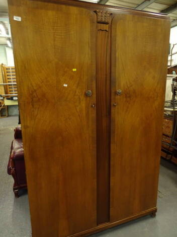 A mid 20thC walnut bedroom suite, comprising double door wardrobe, with moulded centre and shaped handles on shaped feet, 192cm high, 123cm wide, 65cm deep, a further wardrobe and a mirror back dressing table (3).