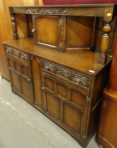 A 20thC oak court cupboard, with central cupboard raised above two frieze drawers and double cupboard beneath, on stylised bracket feet, 136cm high, 137cm wide, 46cm deep.