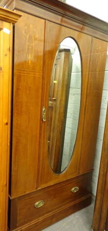 A late Victorian mahogany and boxwood strung wardrobe, with oval mirrored door above drawer beneath, 204cm high, 118cm wide, 49cm deep.