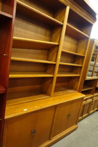 A 20thC oak open bookcase, set with various adjustable shelves, the upper open section raised above cupboards beneath, 215 cm high, 154 cm wide, 41cm deep.