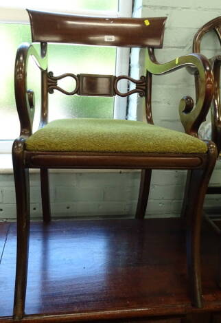 An early 19thC mahogany carver chair, with a bar back scroll, shaped arms and drop in seat with sabre legs, 52cm wide.