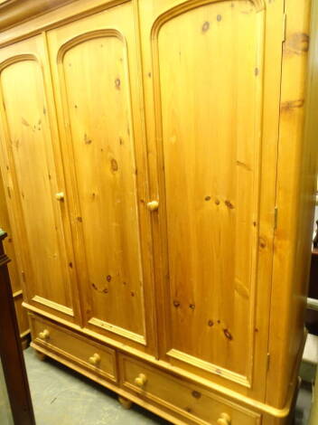 A pine triple door wardrobe with two drawers beneath, 200cm high, 164cm wide, 68cm deep, and a rug.