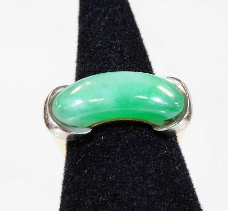 An 18ct white and yellow gold jade dress ring, with curved pale green jade central panel, held by two white gold bands to each end, on a yellow gold band, ring size P, 9.4g all in.