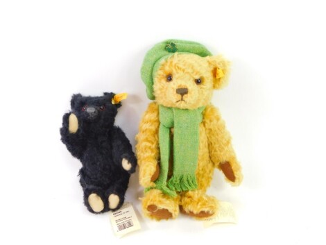 A Steif Club blonde plush jointed teddy bear, with brown velvet style pads and glass eyes, with green scarf, 29cm high and another 660498, in black, each with labels to the ear. (2)