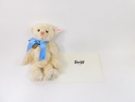 A Steiff Royal Baby plush jointed teddy bear George, in white, with blue bow, label to the ear, stitched under foot, 29cm high, with certificate.