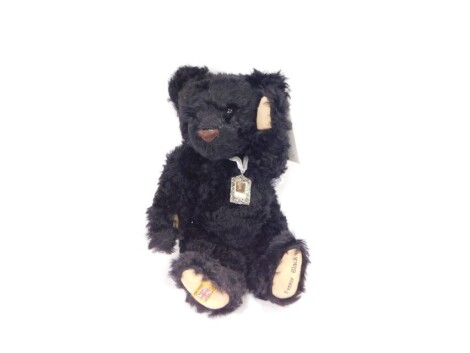 A Merrythought plush jointed Penny Black teddy bear, in black, with faux stamp to the ribbon, BSEN71, 41cm high.