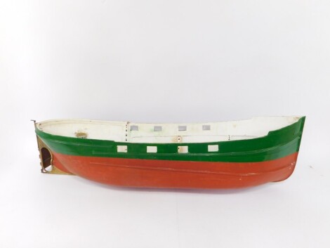 A fibre glass model boat hull, painted in green and terracotta, 119cm wide.