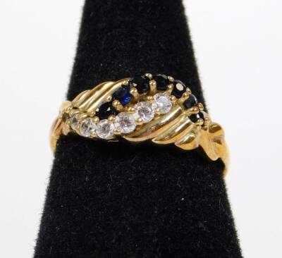 A 9ct gold dress ring, crossover claw set with white and blue stones, size N-O, 2.5g all in.