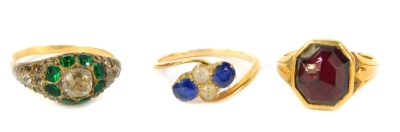 Three gem set dress rings, including sapphire and white stone example, all set in yellow metal.