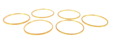 A set of six circular bangles, with chased decoration, unhallmarked yellow metal.