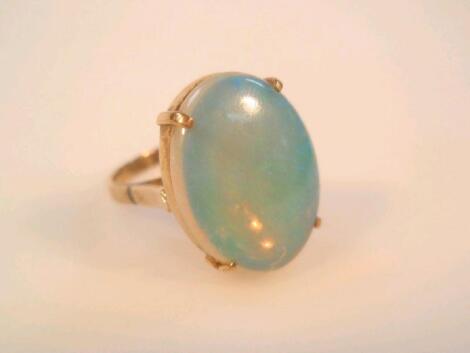 A dress ring set with a cabochon opal (little colour play) in yellow metal