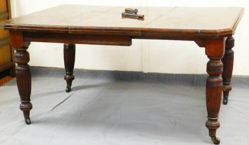 A mid 19thC extending dining table, with canted top on turned legs terminating in castors, 70cm high, 105cm wide, 145cm deep.