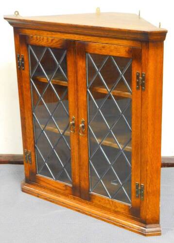 A late 20thC oak hanging corner cupboard, with astragal glazed doors, on a moulded base, with fitted interior, 78cm high, 75cm wide, 52cm deep.