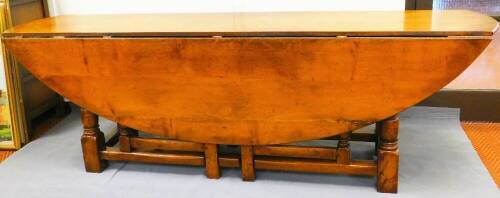 A George III style oak gateleg wake table, with curved top, double gateleg action, turned legs and block feet, when closed, 73cm high, 214cm wide, 55cm deep.