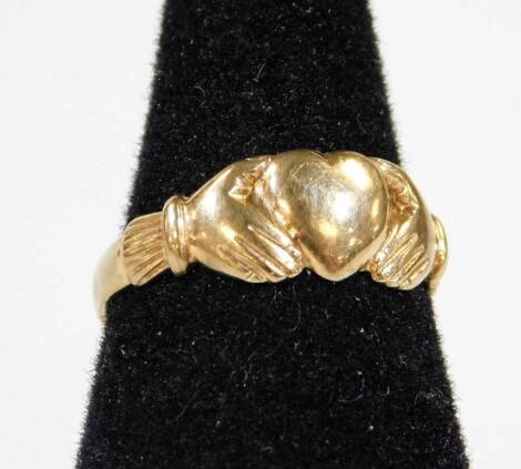 A 9ct gold ring with heart and hand emblem, size L-M, 2g.