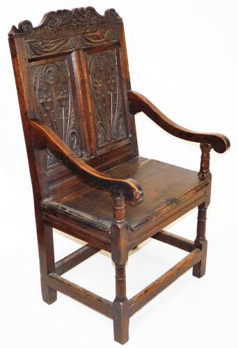 A principally late 17thC oak Wainscot chair, with a scroll cresting rail, raised above two panels of flowers, with scroll arms on turned supports, the plain seat raised turned on turned legs, terminating in block feet, joined by block stretchers, with lat