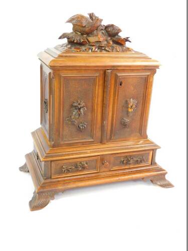 A late 19thC Black Forest wooden cigar chest, the top carved with game birds, above two doors opening to reveal nine sliding shelves, above a frieze drawer, raised on leaf scroll feet, 45cm H, 29.5cm W, 16cm D.