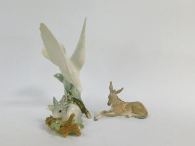 A Lladro porcelain figure of a bird, modelled on a bough, 27cm high, together with an ass 16.5cm wide, and a rabbit 11cm wide. (3)