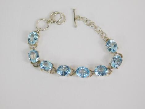 A silver and blue topaz eight stone bracelet, on a ring and t bar fittings, 32ct, with certificate.