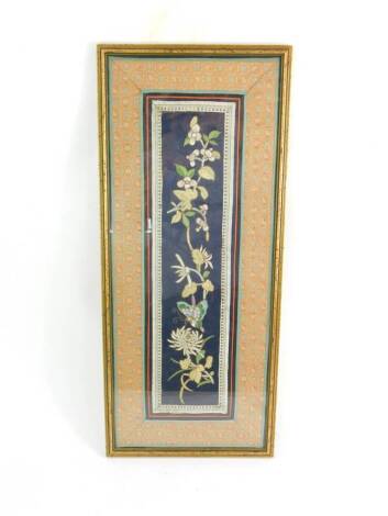 A Qing Dynasty silk sleeve panel, stitched with a butterfly and flowers, against a blue ground, framed, 60cm H, 24cm W.