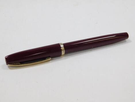 A Sheaffer fountain pen, in burgundy with banding and shaped clip, and partially enclosed nib, 14cm W.