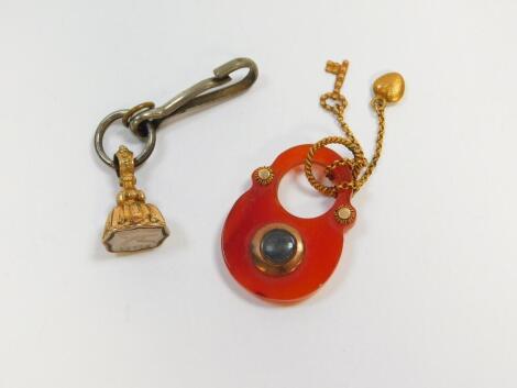 A red agate padlock form hair locket pendant, with heart and key attachments in yellow metal, together with a gilt metal fob seal, the white agate intaglio decorated with a dove beneath the word "Peace" (2).