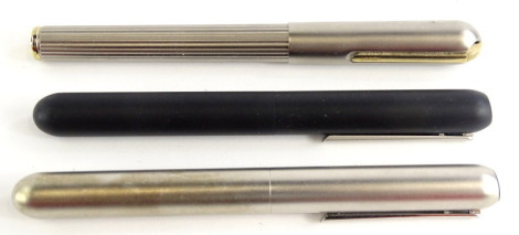 Three Lamy matt metal bullet shaped fountain pens, one with ribbed body, one in black, the other silvered.