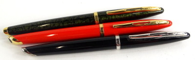 Three Waterman fountain pens, one with green and gold marbled effect, one black, one orange respectively, two with gold plated mounts.