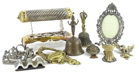 A collection of metalware, an Indian silvered metal and brass scroll holder, various other metalware, to include a hand shaped paper clip, lion mask door knocker, Eastern carved bell, a set of four novelty napkin rings, each applied with lions and persona