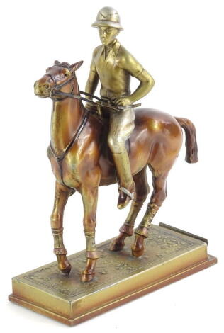 A cold painted spelter figure of a polo player on horseback, on a rectangular base, with a slot possibly for a menu, 15cm wide.