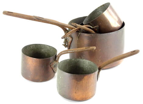 A collection of copper saucepans, each with silvered interior and a shaped iron handle, various sizes.