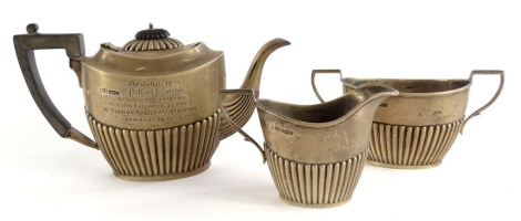 An Edwardian silver three piece tea set, with part fluted decoration, the teapot with ebonised knop and handle, presentation engraving for 'Mr Clifford E. Garrod by his friends for his valuable service as Station Master at Gosberton from 1897-1906,' Sheff