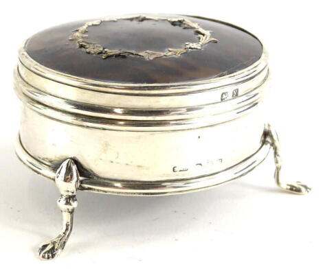 An early 20thC silver and tortoiseshell trinket box, the hinged circular lid with piquet decoration of laurel leaves, marks indistinct, loaded, 6.5cm diameter.