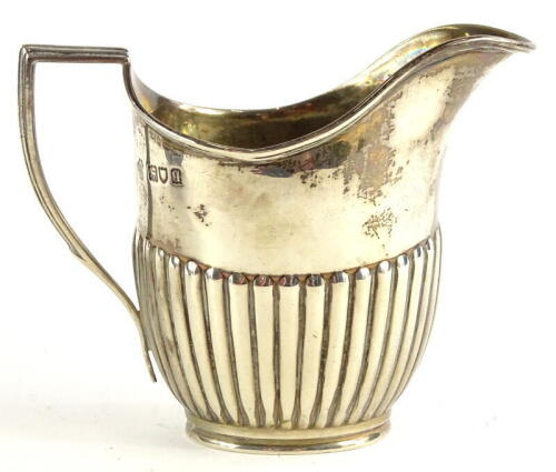 A George V silver part fluted cream jug, with a reeded border and anchored handle, London 1911, 4¾oz.