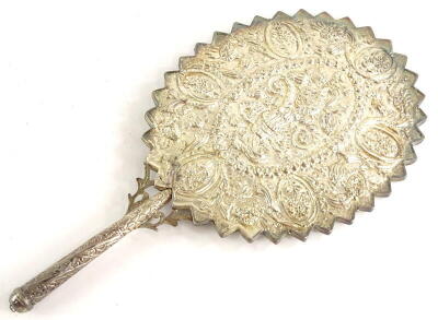 An eastern silver coloured metal hand mirror, embossed with flowers, leaves, etc., and with a jagged edge to the oval frame, mirror plate cracked, (AF).