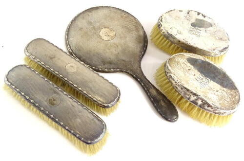 Various silver mounted dressing table items, to include an engine turned hand mirror, lacking mirror plate, and various brushes, (AF).