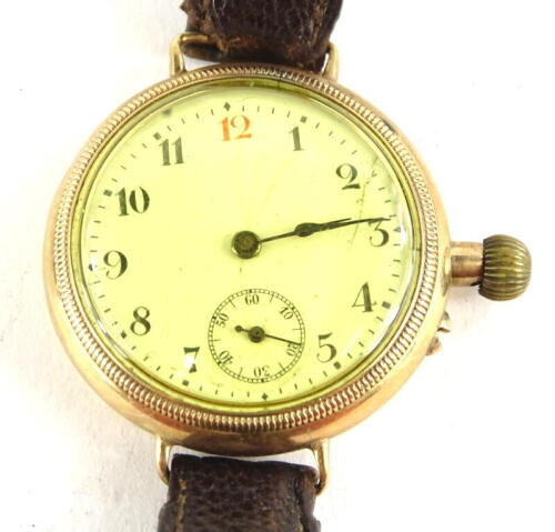 An early 20thC wristwatch, with small circular dial and white enamel watch head, with seconds dial, in yellow metal casing, unmarked, possibly 9ct gold, on a brown leather strap.