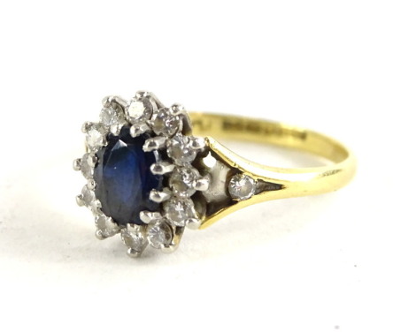 An 18ct gold sapphire and diamond cluster ring, with central oval sapphire surrounded by 12 tiny diamonds, with V shaped shoulders, set with single diamond, ring size R, 4g all in, with original purchase receipt from 2018 for £850.