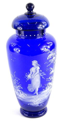 An early 20thC Bristol blue type Mary Gregory design jar and cover, with a dot decoration, set with a figure holding basket, in naturalistic setting, on a stepped circular base, 38cm high.