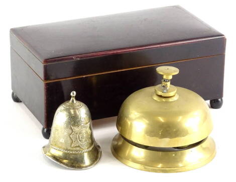 A brass porter's bell, of circular form, with central button, 9cm high, ER helmet bell and a musical cigarette case, of rectangular form (3).